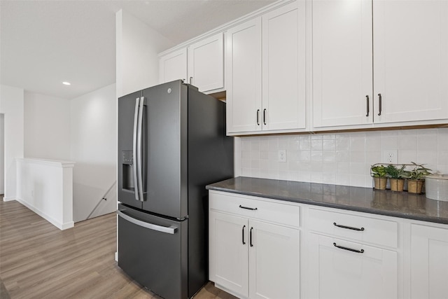 kitchen featuring backsplash, white cabinetry, light wood-type flooring, and stainless steel fridge with ice dispenser