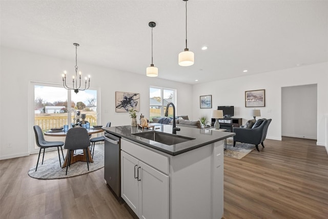 kitchen with sink, dark hardwood / wood-style flooring, white cabinetry, decorative light fixtures, and a center island with sink