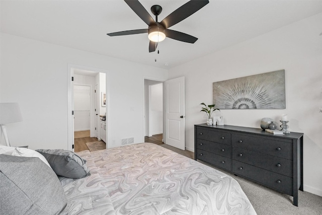 carpeted bedroom featuring ensuite bath and ceiling fan