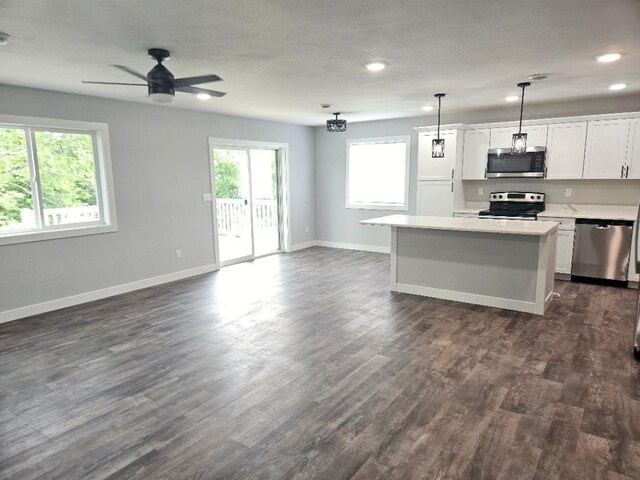 kitchen featuring stainless steel appliances, a center island, hanging light fixtures, a healthy amount of sunlight, and white cabinets