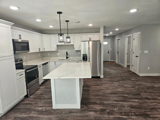 kitchen with stainless steel appliances, white cabinetry, hanging light fixtures, and sink