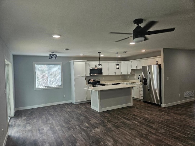 kitchen featuring a kitchen island, decorative light fixtures, sink, white cabinets, and stainless steel appliances