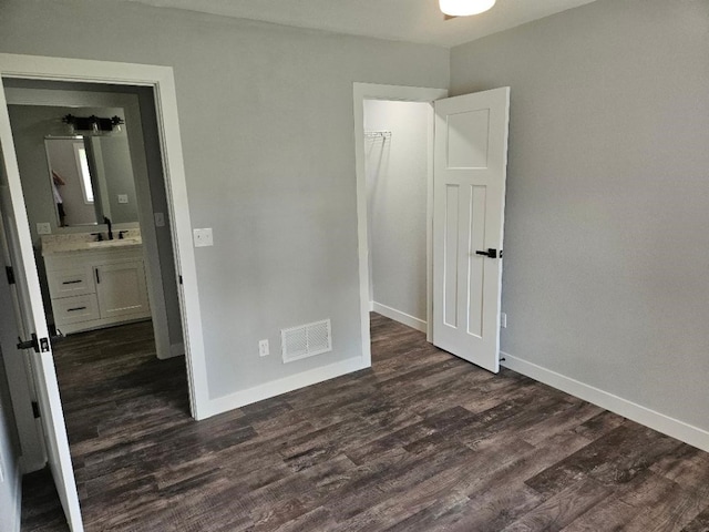 unfurnished bedroom with connected bathroom, dark hardwood / wood-style floors, and sink