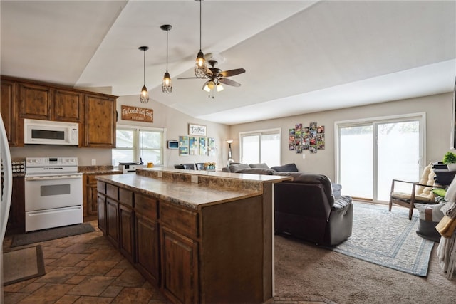 kitchen with white appliances, a center island, vaulted ceiling, and plenty of natural light