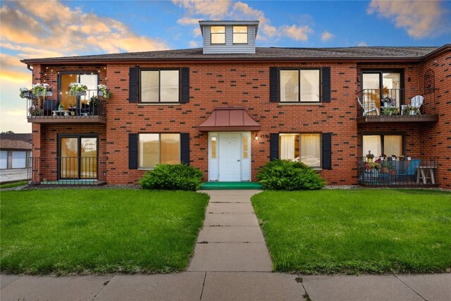 view of property featuring a balcony and a yard