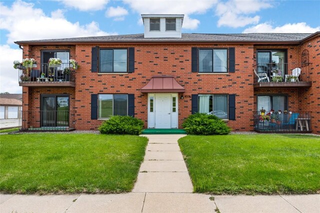 view of property with a balcony and a front yard