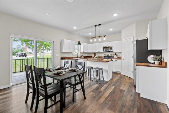 dining space featuring a textured ceiling, dark hardwood / wood-style flooring, and sink