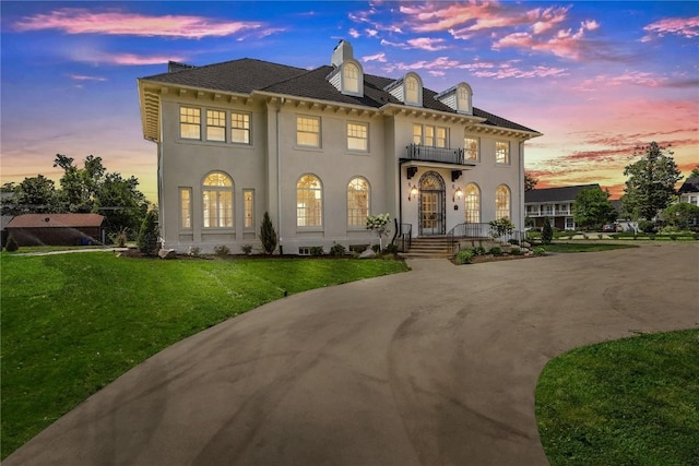 view of front of property with a balcony and a yard