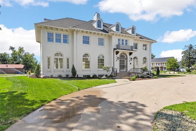 view of front facade with a balcony and a front yard