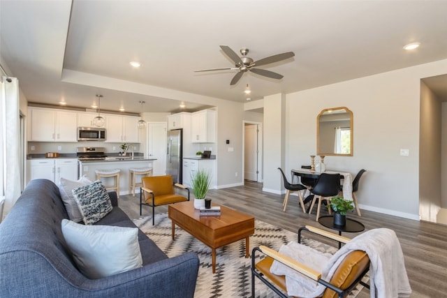 living room with ceiling fan, sink, and dark hardwood / wood-style flooring