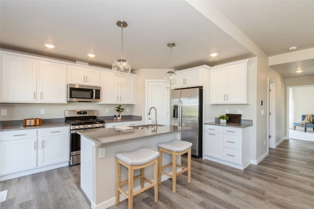 kitchen featuring appliances with stainless steel finishes, a center island with sink, light hardwood / wood-style floors, and white cabinetry