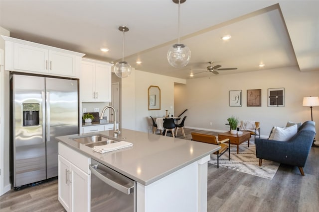 kitchen with white cabinetry, light hardwood / wood-style flooring, stainless steel appliances, and a center island with sink