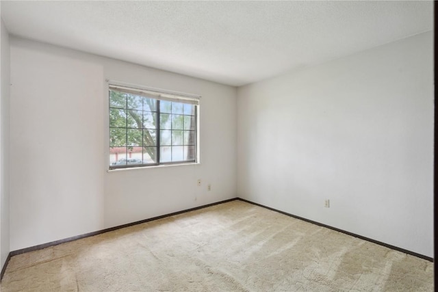 empty room with light carpet and a textured ceiling