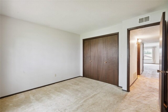 unfurnished bedroom with light colored carpet and a closet