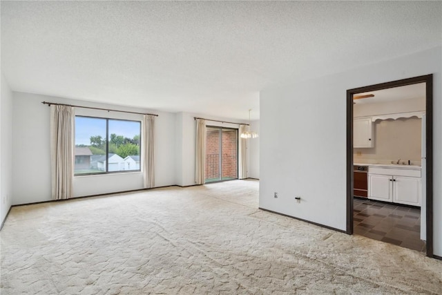 unfurnished room with carpet flooring, sink, and a textured ceiling