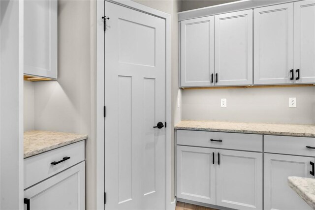 interior space with white cabinets and light stone counters