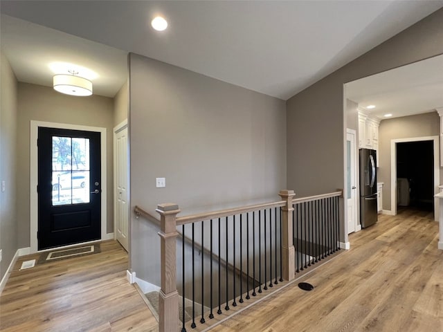 foyer entrance featuring vaulted ceiling and light wood-type flooring