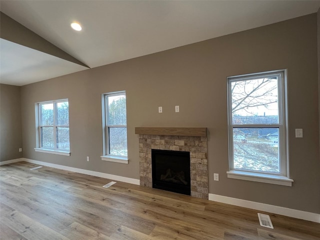 unfurnished living room featuring hardwood / wood-style floors, a fireplace, a wealth of natural light, and vaulted ceiling