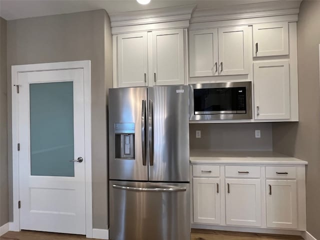 kitchen with white cabinets, hardwood / wood-style floors, and stainless steel appliances