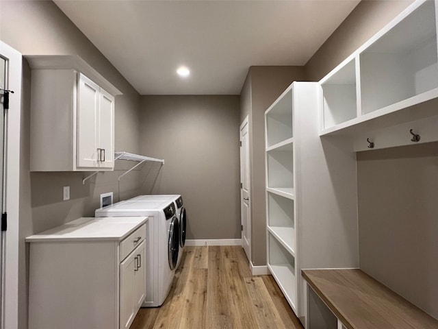 washroom with washer and clothes dryer, cabinets, and light wood-type flooring