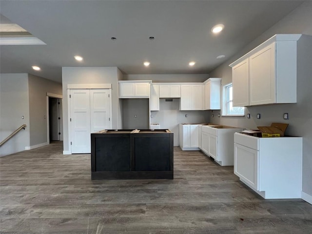 kitchen with white cabinets, a center island, and hardwood / wood-style flooring