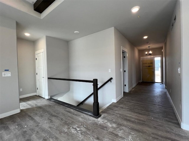 hallway featuring an inviting chandelier and dark wood-type flooring