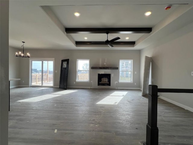 unfurnished living room featuring beamed ceiling, ceiling fan with notable chandelier, and hardwood / wood-style floors