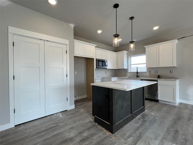 kitchen with stainless steel appliances, decorative light fixtures, a center island, and white cabinets