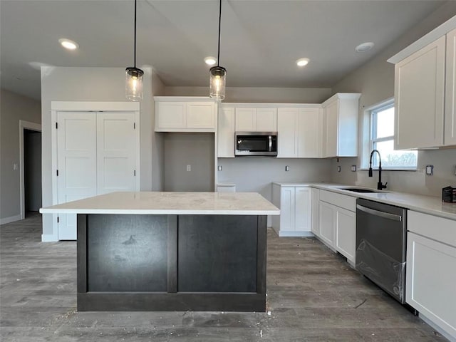 kitchen with sink, decorative light fixtures, appliances with stainless steel finishes, a kitchen island, and white cabinets