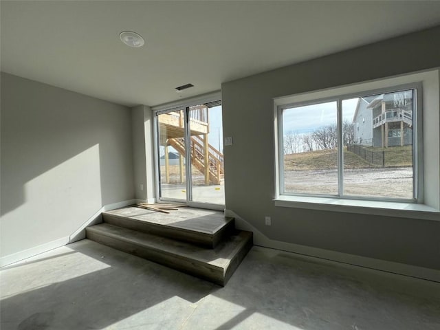 stairs with plenty of natural light and concrete floors