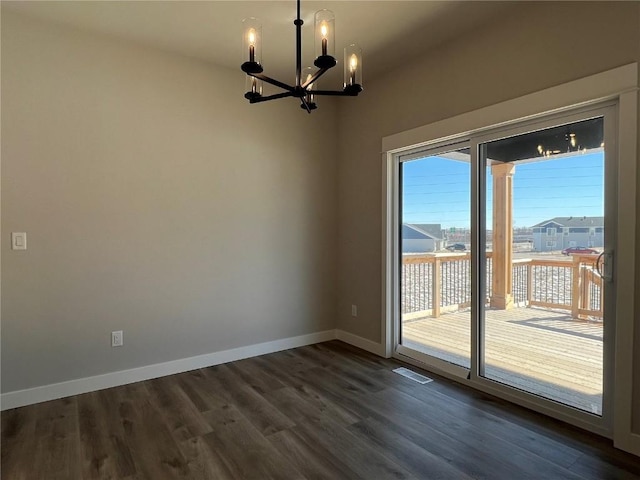 spare room with dark wood-type flooring, visible vents, a notable chandelier, and baseboards