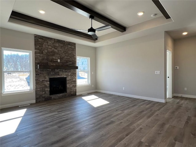 unfurnished living room with baseboards, beamed ceiling, wood finished floors, and a healthy amount of sunlight