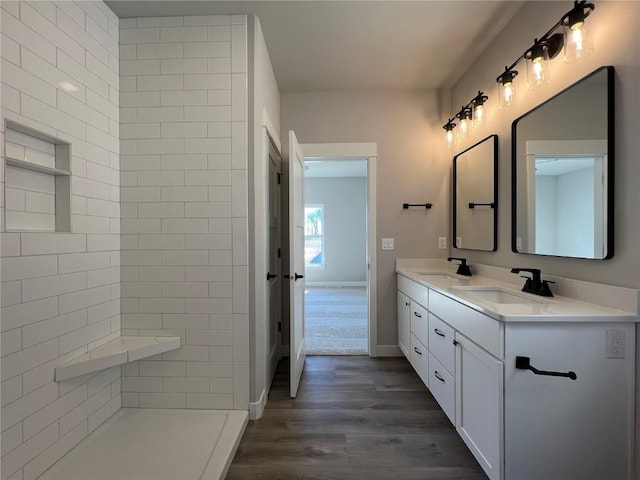 full bathroom with double vanity, baseboards, a sink, and wood finished floors