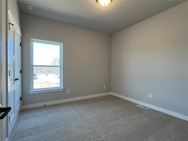 carpeted spare room featuring baseboards and visible vents