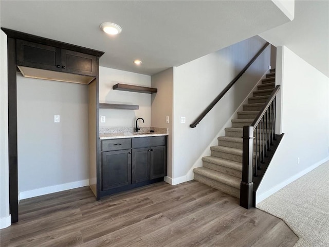 interior space with light wood finished floors, recessed lighting, a sink, baseboards, and stairs