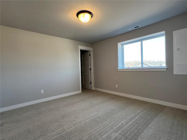 unfurnished room featuring carpet floors, electric panel, visible vents, and baseboards