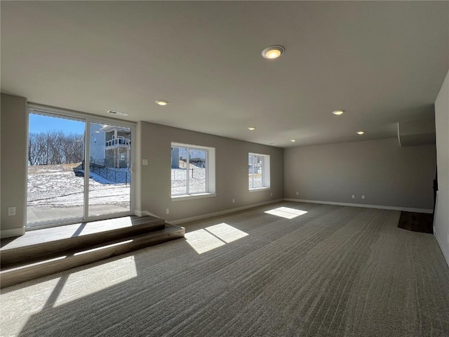 unfurnished living room with carpet floors, recessed lighting, visible vents, and baseboards