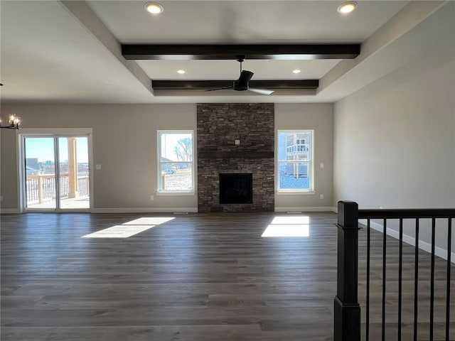 unfurnished living room featuring baseboards, wood finished floors, beamed ceiling, and a stone fireplace