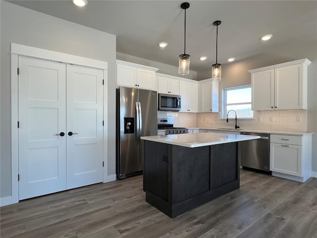 kitchen featuring stainless steel appliances, decorative backsplash, white cabinets, a sink, and a kitchen island