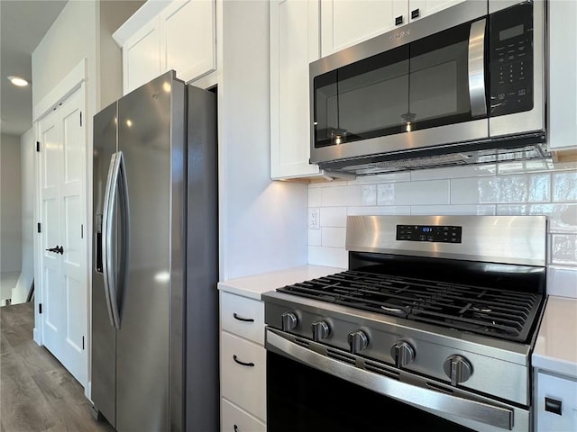 kitchen with decorative backsplash, white cabinetry, stainless steel appliances, and light countertops