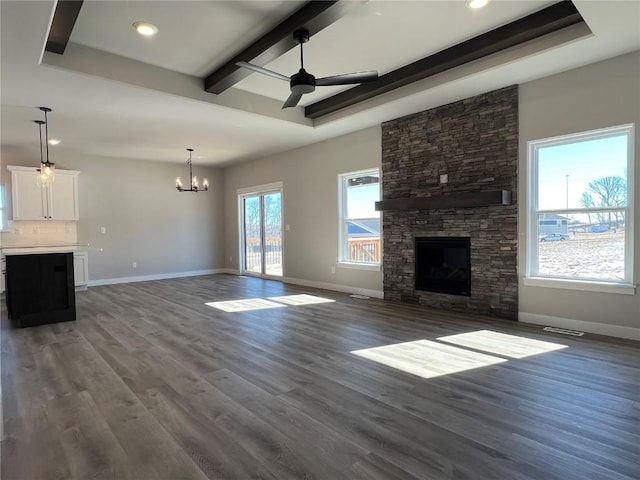 unfurnished living room featuring baseboards, wood finished floors, a fireplace, beam ceiling, and ceiling fan with notable chandelier