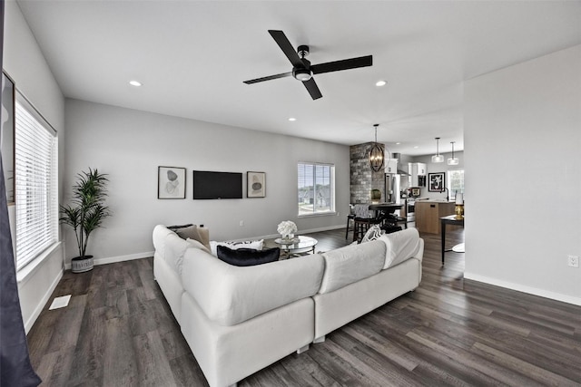 living room with ceiling fan with notable chandelier and dark hardwood / wood-style floors