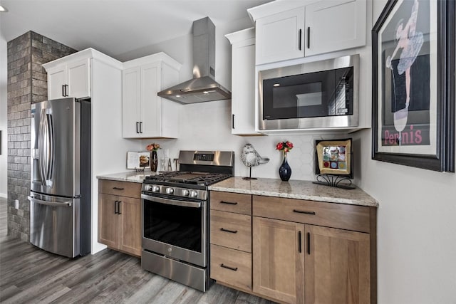 kitchen featuring white cabinets, wall chimney exhaust hood, light stone countertops, dark hardwood / wood-style flooring, and stainless steel appliances