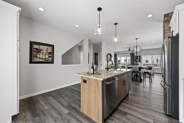 kitchen featuring light stone countertops, an island with sink, stainless steel appliances, and dark hardwood / wood-style floors