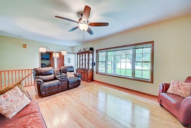 living area with light wood-style flooring, baseboards, and ceiling fan