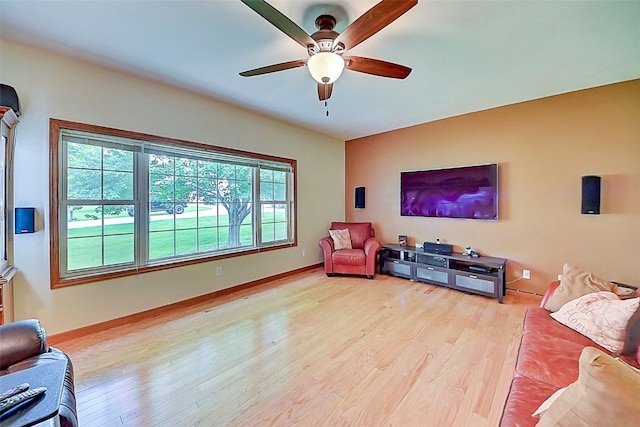 living area featuring baseboards, light wood-style floors, and a ceiling fan