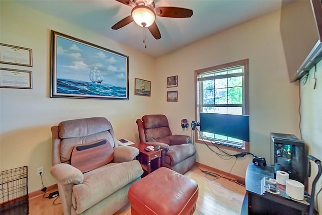 living room featuring baseboards, wood finished floors, and a ceiling fan