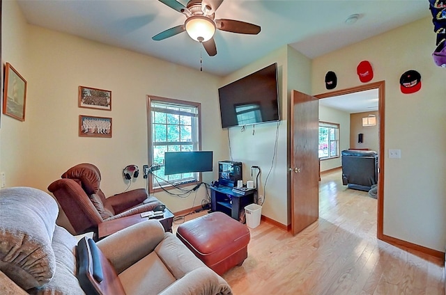 living area featuring a ceiling fan, light wood-type flooring, and baseboards