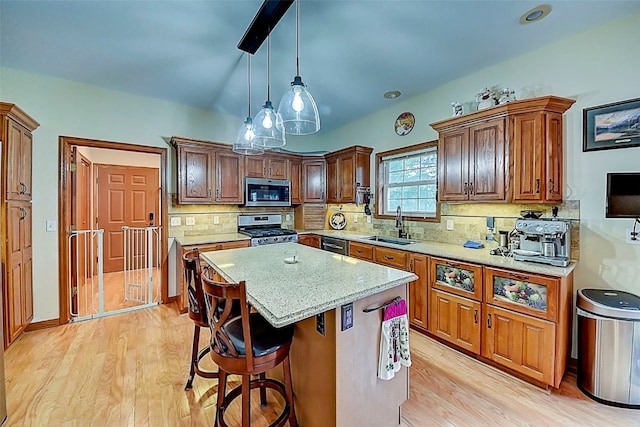 kitchen featuring a sink, light wood-type flooring, a kitchen island, and appliances with stainless steel finishes