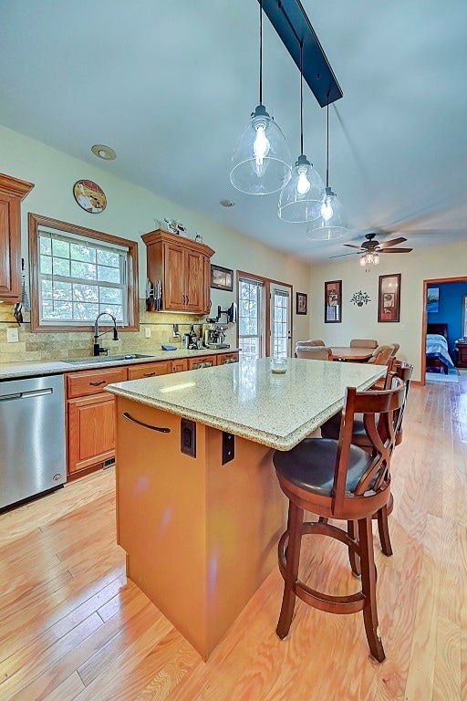 kitchen with a sink, stainless steel dishwasher, a healthy amount of sunlight, and a center island